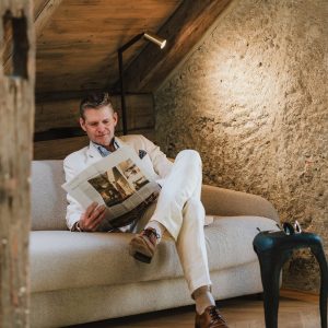 Gast liest entspannt auf Couch im Apartment der H5 Studios by Hotel Grauer Bär Innsbruck.