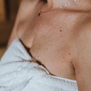 Frau in weißem Saunatuch schwitzt in der Sauna im Wellnessbereich des Partnerhotels Grauer Bär Innsbruck, bei Aufenthalt in den H5 Studios.