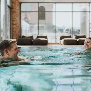 Zwei Personen genießen den Innenpool des Wellnessbereichs im Partnerhotel Grauer Bär Innsbruck bei Buchung der H5 Studios.